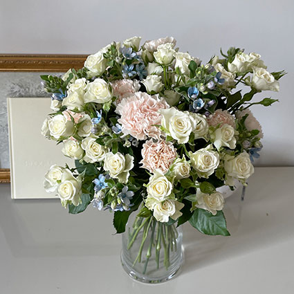 Ziedu pušķis no baltām rozēm, neļķēm un ziliem smalkziediem
