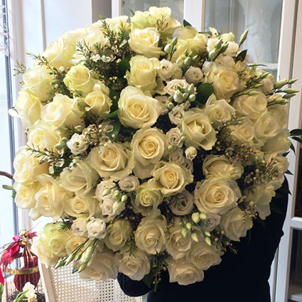 Flowers delivery. Charming bouquet of white roses and white lisianthus with lace of light waxflower