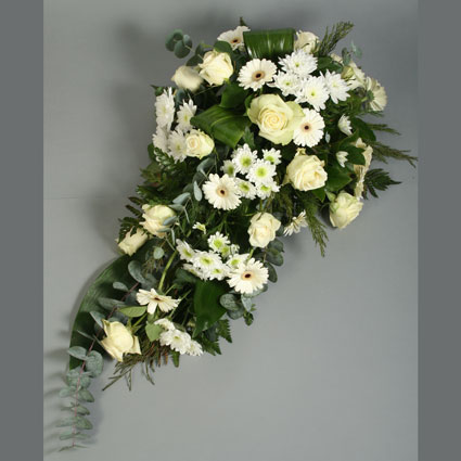Flowers. Funeral flower arrangement of white gerberas, white roses, white chrysanthemums and decorative foliage.