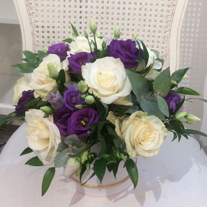 Flowers delivery. Flower box with white roses, blue lisianthus and decorative foliage.