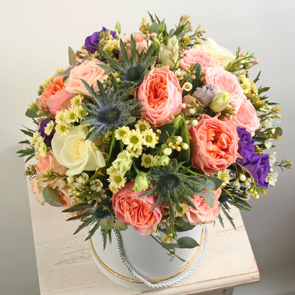 Flowers in Riga. Flower arrangement of peach roses, white roses, blue lisianthus, pink spray roses and decorative foliage.