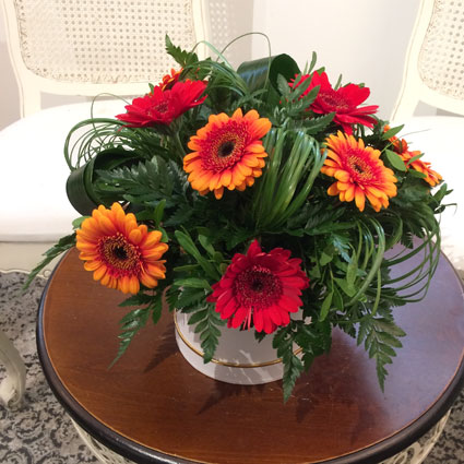 Ziedu kastītē sārtas un oranžas gerberas ar dekoratīviem zaļumiem, ir iespējama ziedu piegāde
