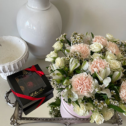 Elegant arrangement of roses, carnations and other decorative flowers in a box and chocolate truffles