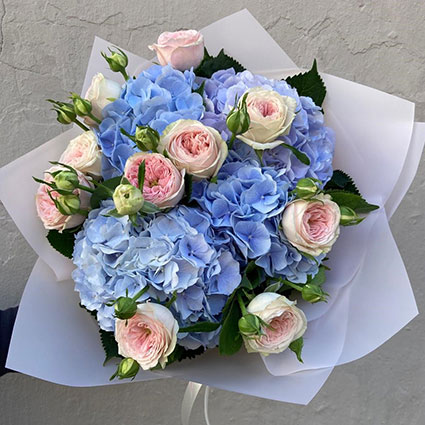 Bagātīgs ziedu pušķis no rozā peonijveida rozēm un zilām hortenzijām