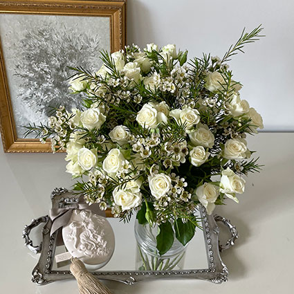 Ziedu pušķī rozes un balti smalkziedi.